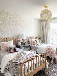 two twin beds in a bedroom with white walls and carpeted flooring, one has a pink teddy bear on the bed