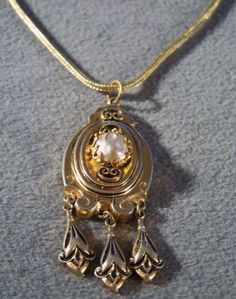 I am offering you this fabulous Victorian-style vintage yellow gold tone wide unique design lavaliere style necklace. It is a bold wonderful design that has such movement and flexibility to it , and such a gorgeous ornate design. Just look at the endless amounts of scrolled etched designs here, accented with jet black enameling. It is also accented with a faux pearl. Creating this dangle lavaliere section of this necklace, creating a wonderful shape giving this amazing necklace such added intere Gold Evening Jewelry With Large Pendant, Vintage Long Necklace For Evening, Elegant Gold Chain Necklace With Vintage Charm, Vintage Chain Necklace For Evening, Collectible Gold Necklace With Intricate Design, Vintage Necklace With Large Pendant For Evening, Elegant Pendant Chain Necklace With Vintage Charm, Antique Gold Costume Jewelry Necklace For Formal Occasions, Gold Jewelry With Vintage Charm For Evening