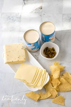 crackers, cheese and milk are sitting on a marble countertop next to two bowls with chips