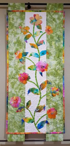 a quilted wall hanging with flowers on it