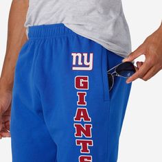 Show your true colors while crushing it in the gym or crushing a nap at home in these New York Giants Team Color Sweatpants. Features All-over, team-colored design so you can rep the team in style Team logo display on upper left leg, in case there were any doubts where your allegiances lie Vertical, stacked and team-colored team wordmark display on left leg so you can show off your team pride with every stride Elastic waistband to keep you comfortable Details Material: 65% Cotton/35% Polyester O Blue Team Spirit Sports Bottoms, Sporty Cotton Bottoms For Game Day, Collegiate Blue Sports Bottoms, Team-colored Bottoms For Game Day, Team-colored Sports Bottoms With Team Name, Sportswear Pants With Letter Print For Sports, Blue Cotton Bottoms For Sports Events, Athleisure Activewear For Team Events And Sports Season, Athleisure Activewear For Sports Season And Team Events