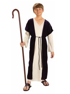 a young boy dressed in an old fashioned monk costume and holding a cane with both hands