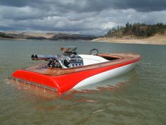 a red and white boat in the water with an engine on it's side