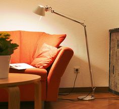 a living room with an orange couch and a lamp on the floor next to it