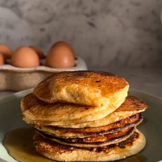 three pancakes stacked on top of each other with eggs in the backgroung