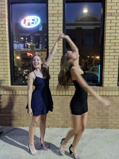 two young women dancing in front of a store