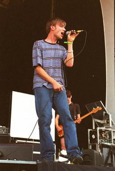 a man standing on top of a stage holding a microphone in his hand and singing