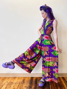 "70's Bright Purple Rainbow Floral Psychedelic Palazzo Sleeveless Jumpsuit Soft and flowy, these majorly wide leg palazzo pants are a 70's dream in a jumpsuit. A subtle V neck and sleeveless makes this a fun piece to layer under for all seasons. The bright colors are so fun and will guarantee you to be the light in any room! Shiny, silk, nylon type material with a lined bodice, nice condition.  14\" Shoulders 32-34\" Bust 28\" Waist 32\" Torso Length 38-44\" Hips 58\" Total Length" Bohemian Fitted Wide Leg Jumpsuits And Rompers, Retro Jumpsuits And Rompers With Retro Print For Summer, Hippie Sleeveless Jumpsuits And Rompers For Spring, Multicolor Retro Sleeveless Jumpsuits And Rompers, Vintage Summer Jumpsuits And Rompers For Party, Vintage Jumpsuits And Rompers For Summer Party, Vintage Summer Party Jumpsuits And Rompers, Retro Sleeveless Floral Jumpsuits And Rompers, Retro Multicolor Full-length Pants