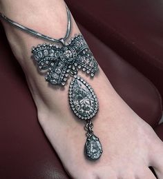 a woman's foot with an ornate cross tattoo on the side of her leg