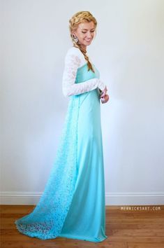 a woman in a long blue dress standing on a hard wood floor with her hand on her hip