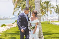 a man and woman standing next to each other in front of palm trees