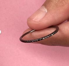 a person's hand holding a ring with black diamonds on it and the word love spelled in white letters