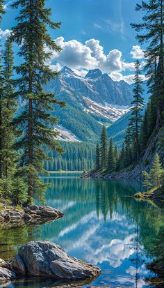 a mountain lake surrounded by pine trees and mountains in the distance with clouds reflected in the water