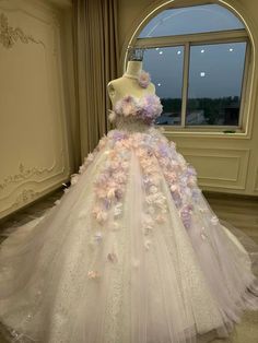 a dress made out of flowers is displayed in front of a large window with curtains