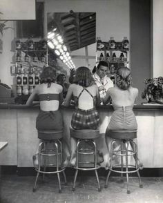 three women in bathing suits are standing at the bar