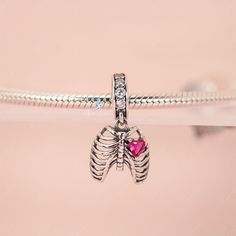 This is charm only, bracelet is sold separately. Experience true love with this exquisite pendant charm featuring a silver rib cage adorned with a stunning pink heart stone. Made of high-quality 925 sterling silver, its polished finish adds a brilliant shine and is accented with a platinum plating. Add this beautiful love oath of rib dangle pendant charm to your bracelet or gift it to your special someone. Materials: 925 sterling silver, cubic zirconiaFinish: platinum plateDimensions: 0.76 x 0.4 Sterling Silver Heart Jewelry With Charms, Sterling Silver Dangle Jewelry With Heart Charm, Silver Heart Charm Jewelry In Cubic Zirconia, Heart-shaped Sterling Silver Jewelry With Silver Clasp, Silver Cubic Zirconia Jewelry With Heart Charm, White Gold Sterling Silver Heart Pendant Jewelry, Sterling Silver Charms With Lobster Clasp For Valentine's Day, Sterling Silver Heart Charms For Valentine's Day, Heart-shaped Sterling Silver Charms For Valentine's Day