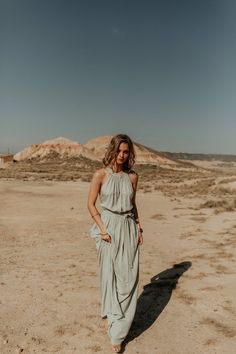 a woman standing in the desert wearing a dress