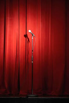 a microphone on stage with red curtains in the background