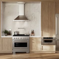 a kitchen with marble counter tops and stainless steel stove top oven, range hood, and refrigerator