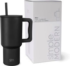 a black coffee mug with a straw in it sitting next to a box and cardboard package