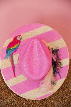 Add a splash of fun and playfulness to your summer wardrobe with the unique Adella sun hat. Made from straw and featuring pink painted stripes, a blue and pink feather combo, and a quirky parrot patch, this hat will surely turn heads and bring a smile to your face. Bring on the sunshine! Playful Handmade Sun Hat For Summer, Playful Brimmed Straw Hat For Summer, Fun Pink Sun Hat For Vacation, Fun Summer Straw Hat With Short Brim, Fun Short Brim Straw Hat For Summer, Playful Pink Mini Hat For Summer, Pink Summer Sun Hat For Kentucky Derby, Playful Pink Summer Hats, Playful Curved Brim Straw Hat For Summer