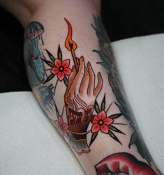 a woman's leg with tattoos on it and a candle in the middle of her arm