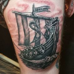 a black and white photo of a man's leg with a pirate ship tattoo on it