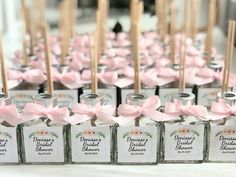 small jars with pink bows are lined up on a table