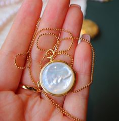 Introducing our unique round locket pendant that combines classic and modern design elements! One side features a beautiful piece of natural mother of pearl while the other side showcases delicate hollow patterns in gold vermeil. This locket opens up to reveal a small space where you can keep a special photo, message, or perfumed ball close to your heart. The natural patterns and elegant glow of each piece of mother of pearl are one-of-a-kind, making this pendant truly unique. The necklace is ad Elegant Gold-plated Medallion Locket Necklace, Elegant Medallion Locket Necklace In Gold Plated, Elegant Gold Plated Medallion Locket Necklace, Elegant Gold-plated Round Locket Necklace, Elegant Gold Round Disc Locket Necklace, Elegant Gold Plated Round Locket Necklace, Timeless Round Locket Necklace As Gift, Luxury Round Pendant Locket Necklace As Gift, Gold Timeless Round Locket Necklace