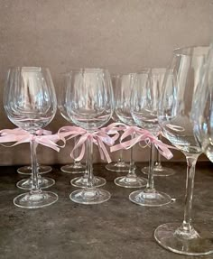 six wine glasses with pink bows are lined up in a row on a counter top