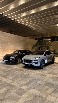 two cars parked next to each other in front of a building with concrete flooring