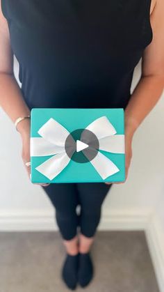 a woman holding a blue box with a white bow