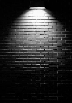 a black and white photo of a brick wall with a light on it that reads rivier