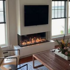 a living room filled with furniture and a flat screen tv mounted on the wall above a fire place