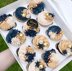 a box filled with blue and white cupcakes on top of a green field