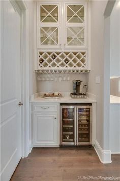 a kitchen with white cabinets and an open wine rack on the wall above the sink