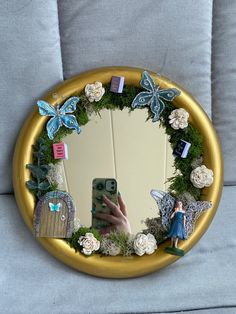 there is a mirror with flowers and fairy figurines on it in the shape of a circle