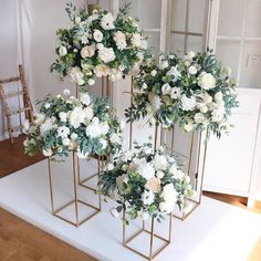 three gold vases with white flowers and greenery