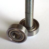 two ball bearing units on a white surface, one with a screw and the other without