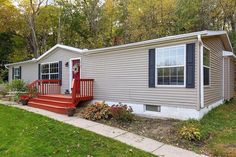 a mobile home with red steps leading up to the front door and stairs leading up to the second floor