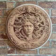 a drawing of a woman's face with snakes around her head on a brick wall