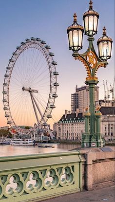 a large ferris wheel sitting on the side of a river next to a light pole