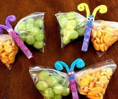 four bags filled with fruit and butterflies on top of a wooden table next to an apple