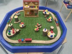 a toy train set on top of a blue table in a playroom with toys