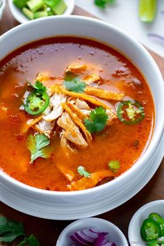 a bowl of chicken tortilla soup with cilantro, limes and jalapenos