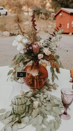 an arrangement of flowers and greenery on a table