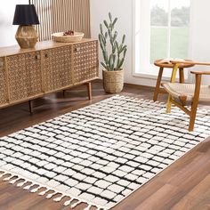 a white and black area rug in a room with wooden furniture, potted plant and large window