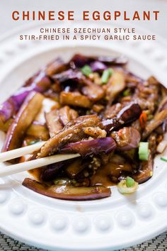 chinese eggplant stir fried in a spicy garlic sauce with chopsticks on a white plate