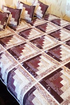 a bed with purple and white quilted bedspread on it's side