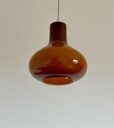 a brown light hanging from a ceiling with a white wall in the backround